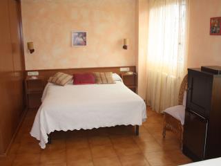 Fotografía de una habitación doble, con la cama, armario, nevera y ventana al exterior
